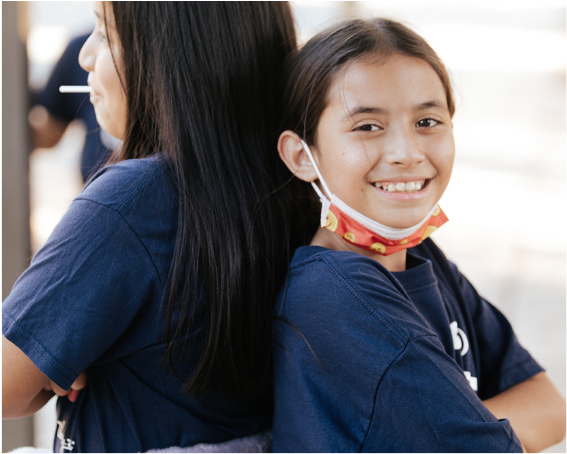 Girls on the Run participants stand back to back with a teammate smiling.